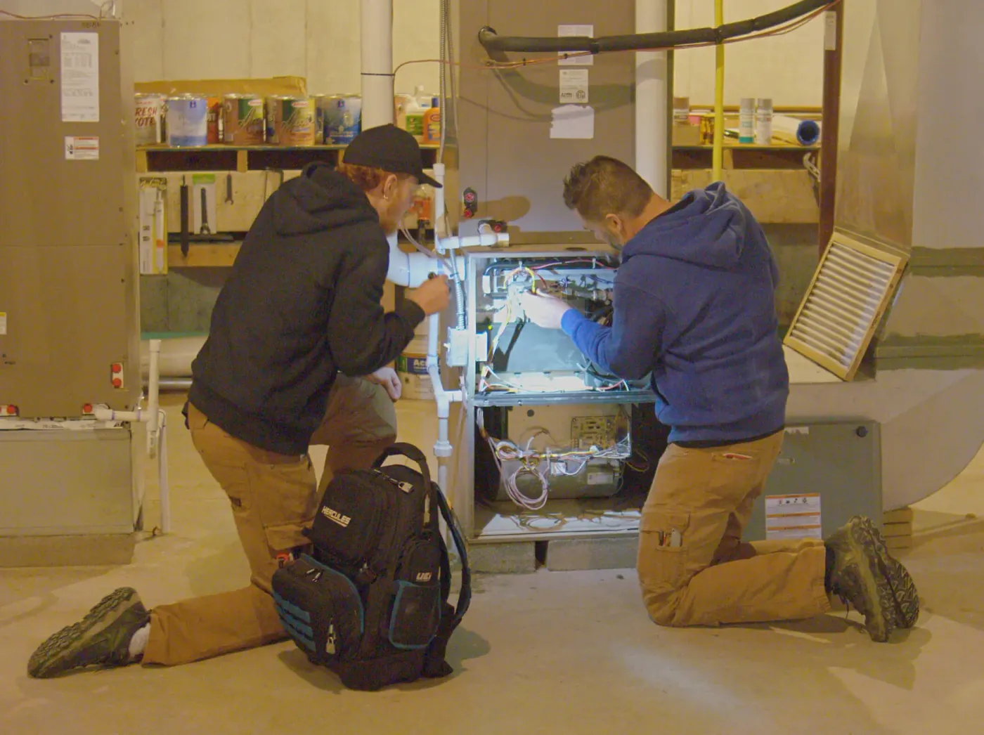 Plumb it Heat it Cool it technicians repairing a gas furnace in a home basement