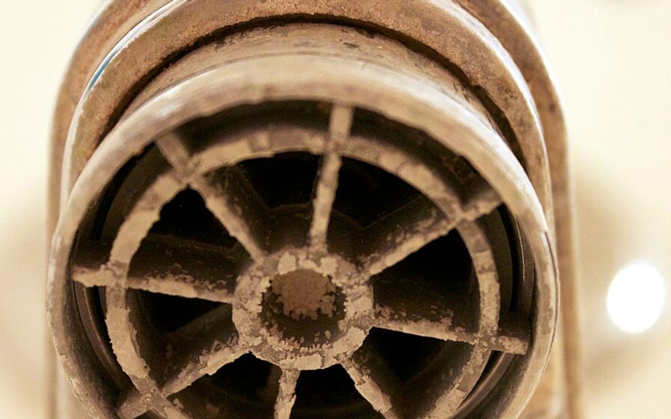A faucet aerator crusted with white hard-water scale.
